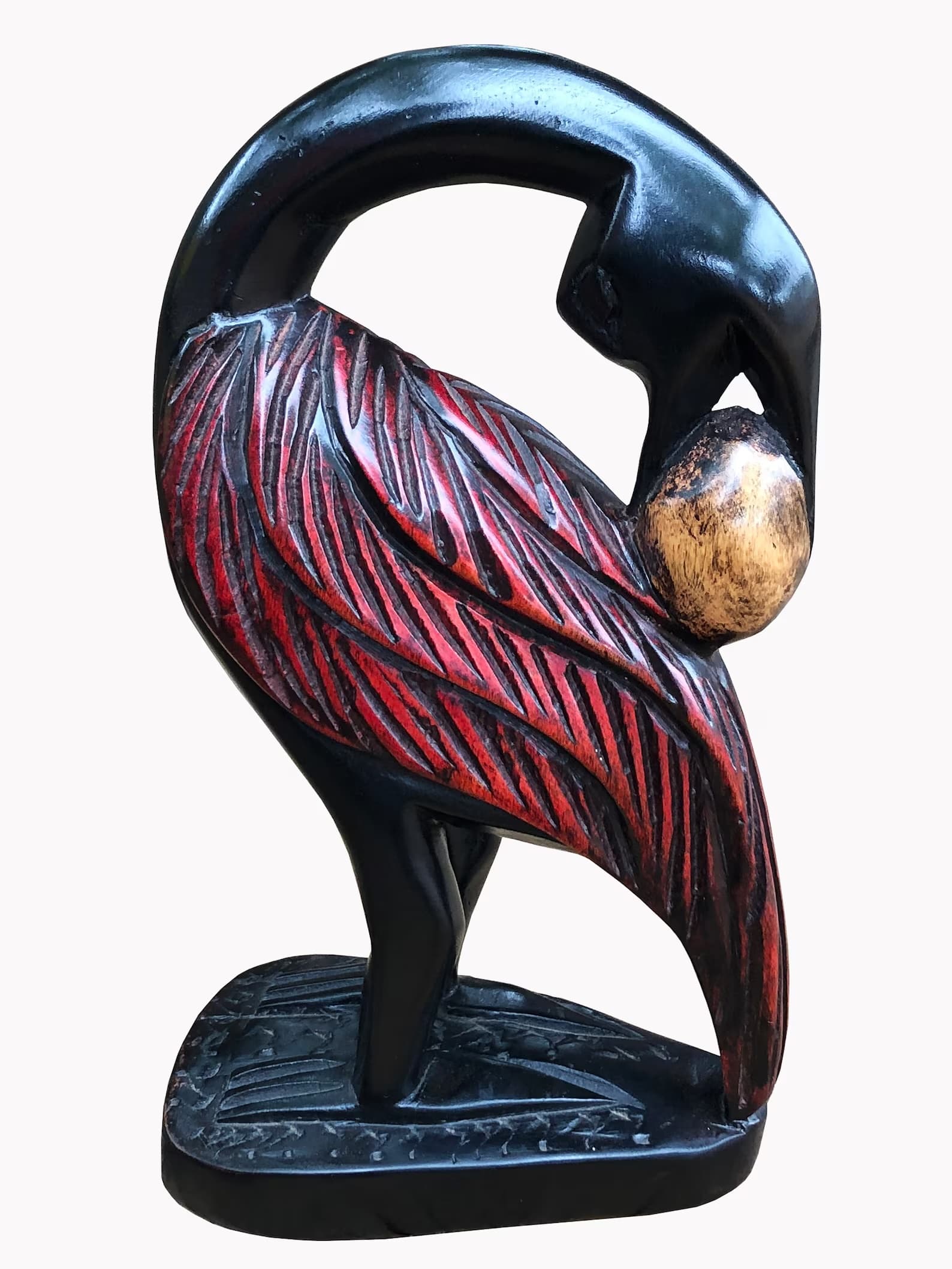 A hand-carved Sankofa bird — ebony body with crimson feathers, turning back to hold a golden egg.